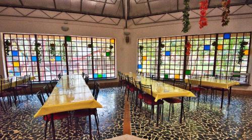 a room with tables and chairs and stained glass windows at Srushti Farms Resort in Vasind
