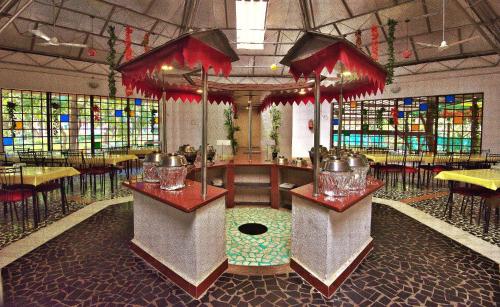 a restaurant with tables and chairs in a room at Srushti Farms Resort in Vasind