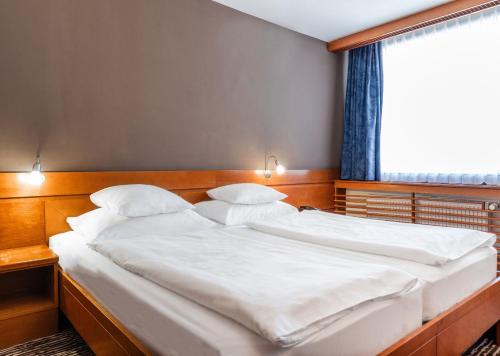 two twin beds in a room with a window at Hotel Kranjska Gora in Kranjska Gora