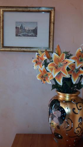 a vase with flowers in it in front of a picture at Maestoso Locazione Turistica in Rome