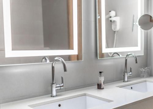a bathroom with two sinks and two mirrors at Hotel Kranjska Gora in Kranjska Gora