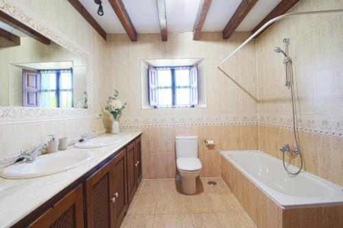 ein Badezimmer mit zwei Waschbecken, einer Badewanne und einem WC in der Unterkunft La Casa del Bosco in Suances