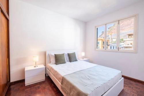 a white bedroom with a bed and a window at Villa Heredia by GALMI in Ribeira Brava