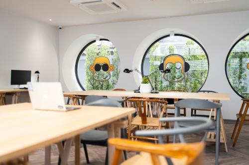 a room with tables and chairs and windows with faces on them at Blu Monkey Hub and Hotel Krabi Town in Krabi town