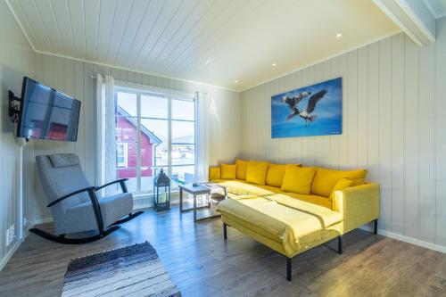 a living room with a yellow couch and a tv at Ure Lodge in Sennesvik