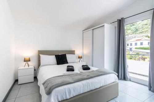 una camera bianca con un grande letto e una grande finestra di Esterinha's Sunset Apartment by GALMI a Estreito da Calheta