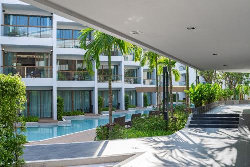 an apartment building with a swimming pool and palm trees at Bella Nara Phuket Naiyang Beach in Nai Yang Beach