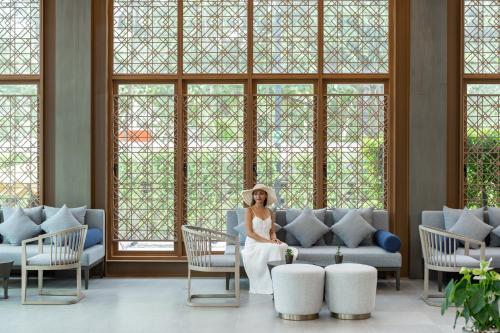 a bride sitting on a couch in a room with windows at Bella Nara Phuket Naiyang Beach in Nai Yang Beach