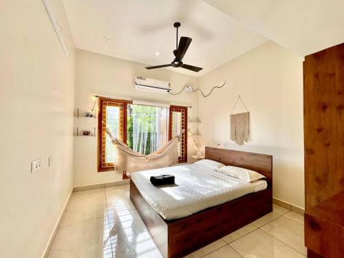 een slaapkamer met een bed en een plafondventilator bij Villa Porto' Lux beach house', Pondicherry in Pondicherry