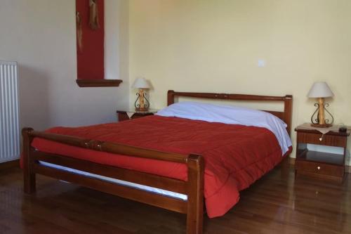 Traditional House in Dimitsana في ديميتسانا: غرفة نوم بسرير وبطانية حمراء ومصباحين