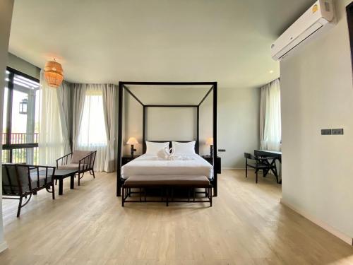 um quarto com uma cama grande, uma mesa e cadeiras em O2 The Residence โอทู เดอะ เรสซิเดนซ์ em Kanchanaburi