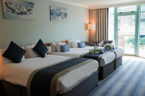 a hotel room with three beds and a couch at De Vere Cotswold Water Park in Cirencester