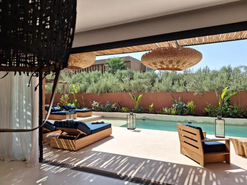 a patio with chairs and a swimming pool at Villa Madjha Ecolodge Marrakech in Marrakech