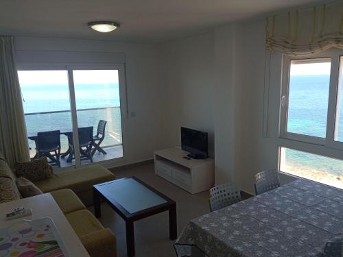een woonkamer met een bank, een televisie en een tafel bij BEACH SUN SPIRIT, spa & gym in La Manga del Mar Menor