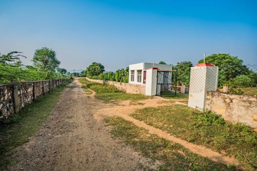 a dirt road next to a retaining wall at Guldaar Sariska - A luxury Forest Resort in Tehla