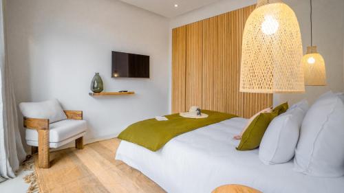 a bedroom with a white bed and a chair at Villa Madjha Ecolodge Marrakech in Marrakech