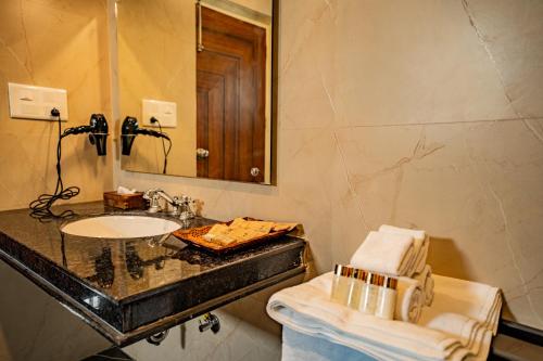 ein Bad mit einem Waschbecken und einem Spiegel in der Unterkunft Guldaar - A Luxury Forest Retreat in Tehla
