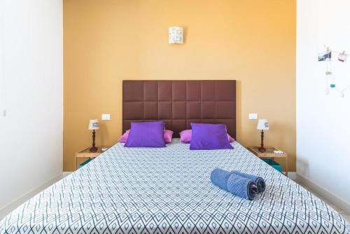 a bedroom with a large bed with purple pillows at Casa Pizquito Agaete con piscina in Agaete