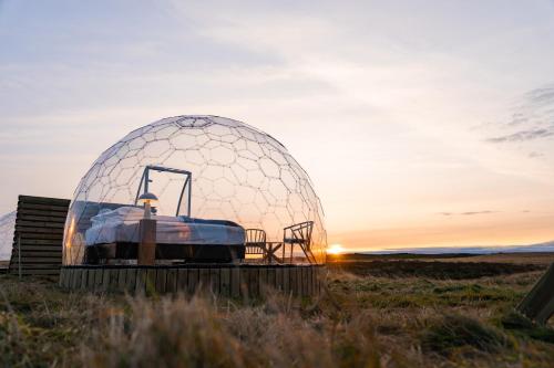 a dome observatory in a field with the sunset in the background at Aurora Igloo South in Hella