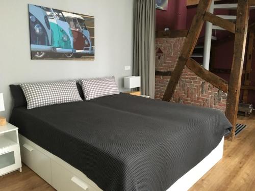 a bedroom with a black bed with a brick wall at Bulli-Suite, 2-Zimmer Maisonette-Wohnung in Haan