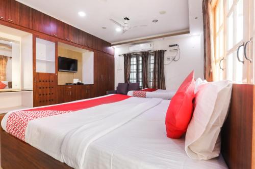 - une chambre dotée d'un grand lit avec des oreillers rouges et blancs dans l'établissement OYO Flagship Maheshwari Villas, à Chennai