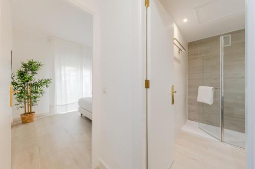 a white bathroom with a shower and a glass door at Alojarte Bécquer recien reformado Free parking in Seville