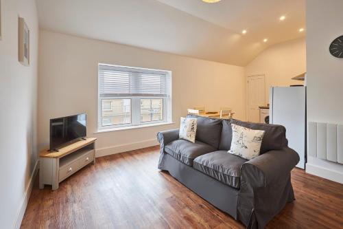 a living room with a couch and a television at Host & Stay - Main Street Apartments in Seahouses