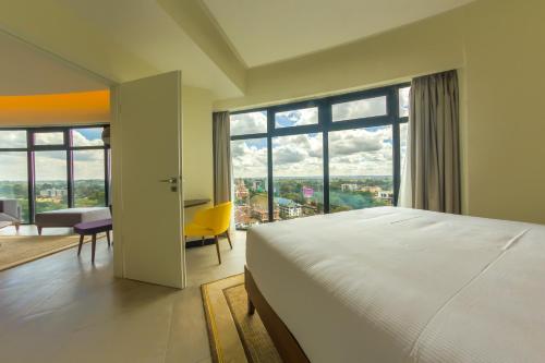 um quarto com uma cama grande e uma janela grande em Prime Living Luxury Apartments em Nairobi