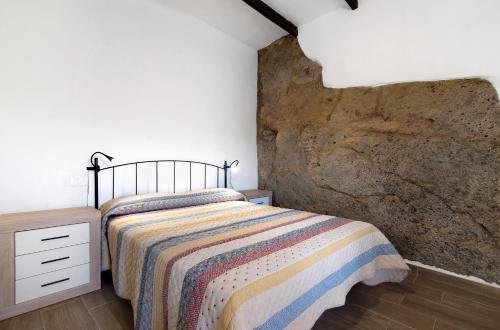 - une chambre avec un lit et un mur en pierre dans l'établissement Casa Pepa, à Santa Brígida