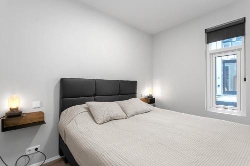 1 dormitorio con 1 cama con cabecero negro y ventana en Grandinn Luxury apartment in Downtown Reykjavík, en Reikiavik