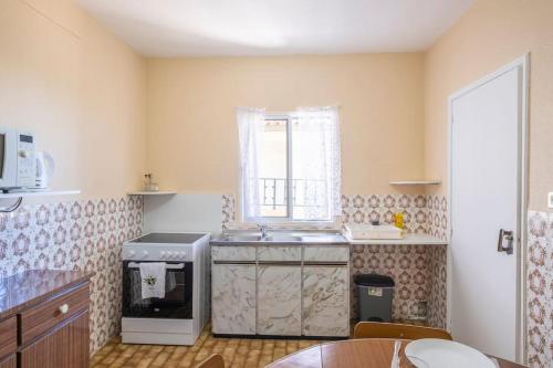een keuken met een wastafel, een fornuis en een raam bij Villa Pequenino by GALMI in Estreito da Calheta