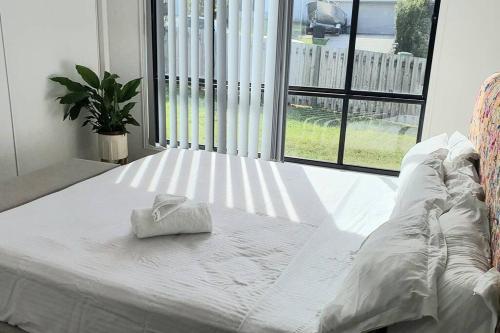 a white bed with a towel on it in front of a window at Kumera Home in Gold Coast