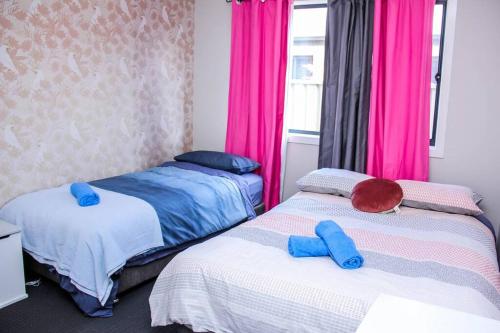 two beds in a room with pink curtains at Wetland Gem in Wonthaggi