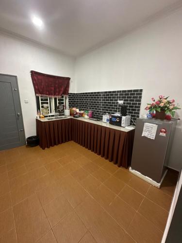 a room with a kitchen with a counter and a refrigerator at DHIA HOMESTAY in Machang