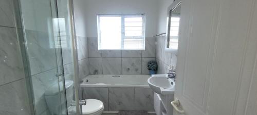 a bathroom with a tub and a toilet and a sink at 19 Tontiki in Ballito
