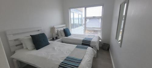 two beds in a white room with a window at 19 Tontiki in Ballito