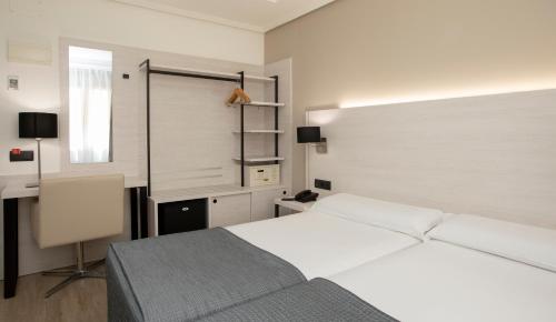 a bedroom with a white bed and a desk at Porcel Ganivet in Madrid