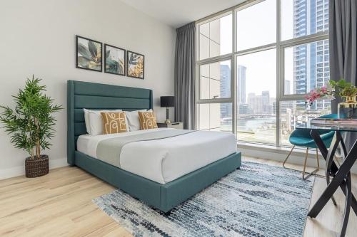 a bedroom with a bed and a desk and windows at Frank Porter - Continental Tower in Dubai