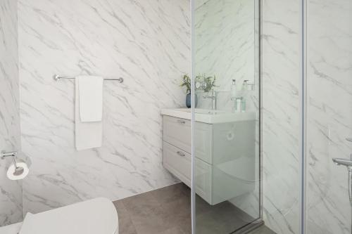 a white bathroom with a sink and a shower at Frank Porter - Continental Tower in Dubai