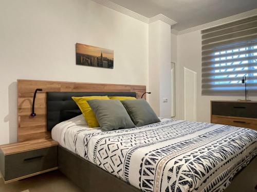 een slaapkamer met een bed met een houten hoofdeinde en een raam bij Apartamento en Arahal Sevilla in El Arahal