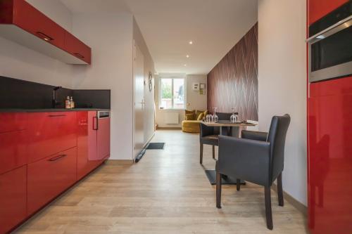 une cuisine avec des placards rouges et une table avec des chaises dans l'établissement L'escapade balnéo, à Béthune