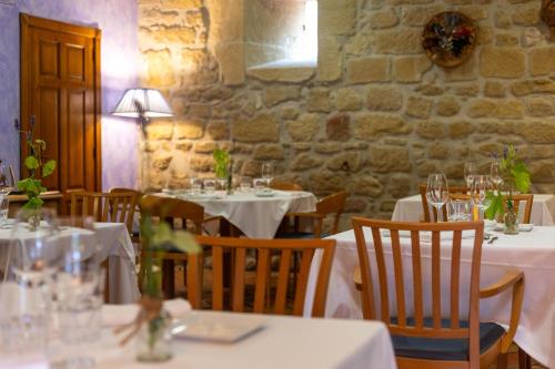 a restaurant with white tables and chairs and a stone wall at Hotel Villa de Ábalos in Ábalos
