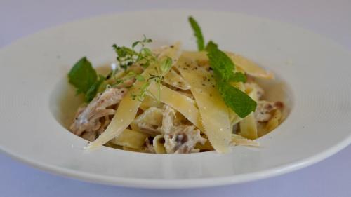 a bowl of pasta with meat and cheese on a white plate at Gościniec Uniejów in Uniejow