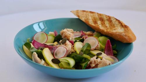 a salad in a blue bowl with a piece of bread at Gościniec Uniejów in Uniejow