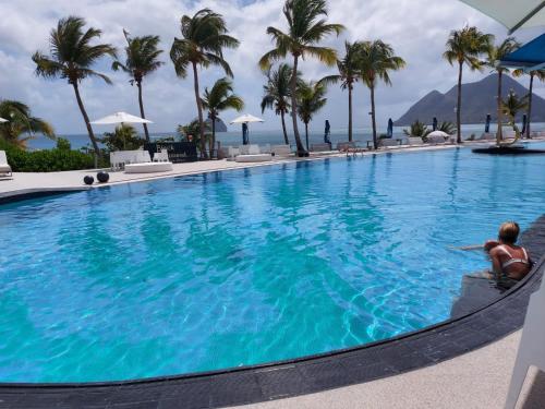 ル・ディアマンにあるCharmant appartement avec piscine et vue sur merのリゾートのプールに座っている男