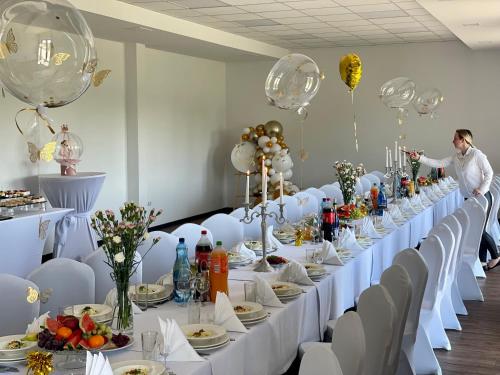a long table with white table cloths and balloons at Gościniec Uniejów in Uniejow