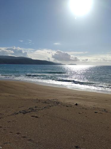 a beach with the sun shining on the water at Tapia Hills in Methoni
