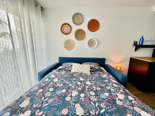 a bedroom with a blue bed with a floral blanket at Studio le petit écureuil in Carnac