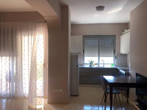 eine Küche und ein Esszimmer mit einem Tisch und einem Fenster in der Unterkunft Center Apartment in Vlorë