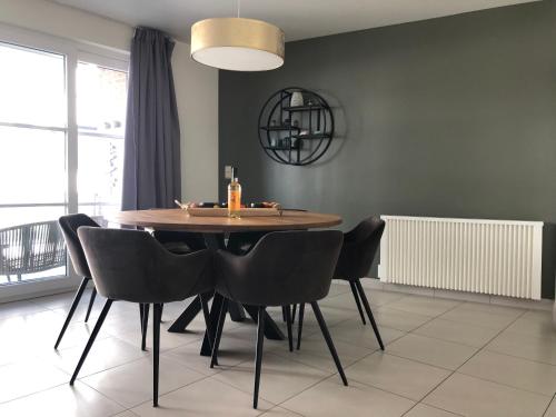 a dining room with a wooden table and black chairs at Gezellig appartement op 400m van zee Oostende-Mariakerke Bad in Ostend